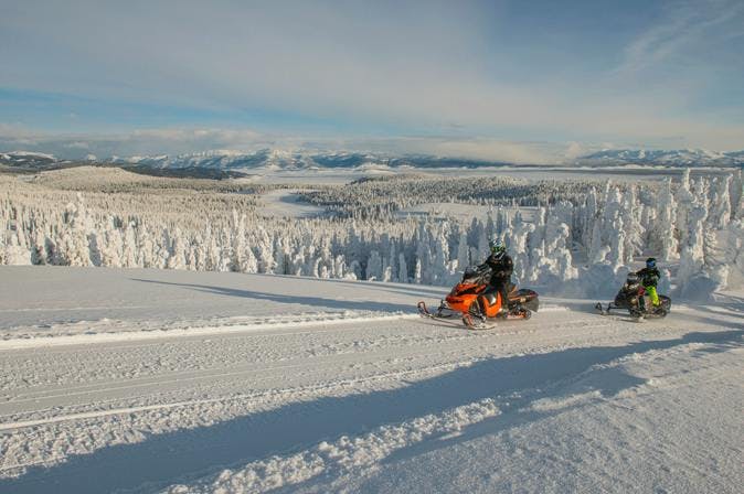 Source: Destination Yellowstone. Snowmobilers crossing the frozen lanscape in Island Park, Idaho.