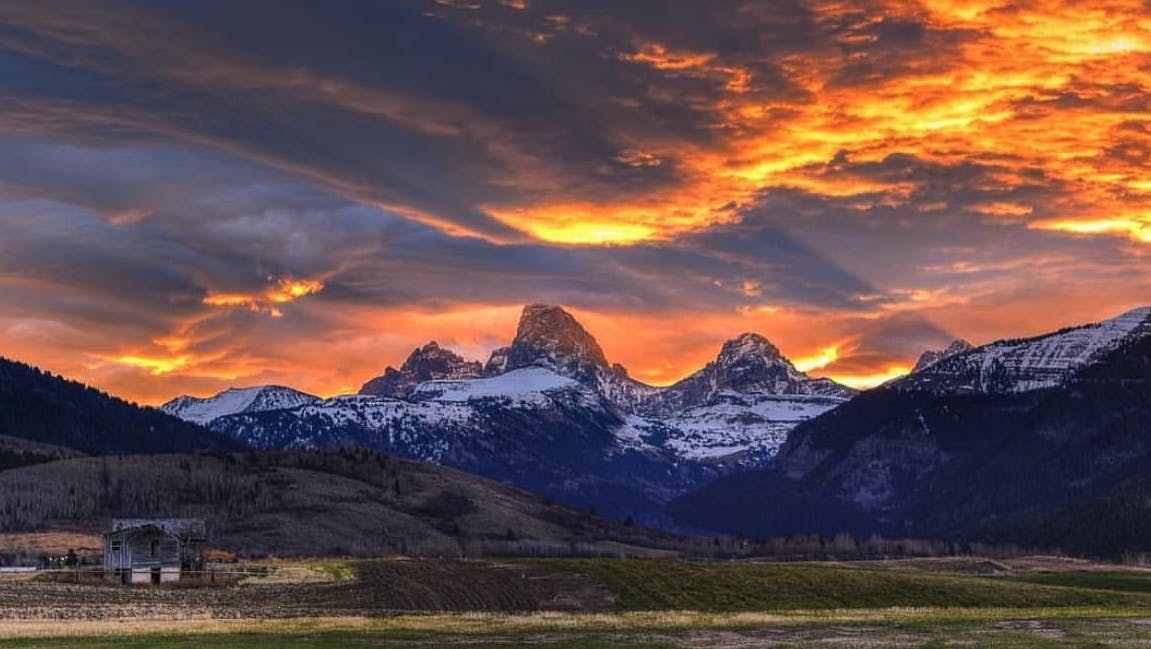 Photo by Jason Husband of the sun over the Teton Mountains through the clouds in Teton Valley, a part of Eastern Idaho and Yellowstone Teton Territory.