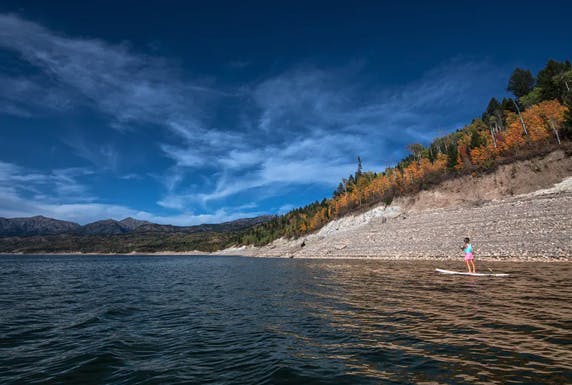 A woman paddle boards on the Palisades Reservoir in Swan Valley in Eastern Idaho, a part of Yellowstone Teton Territory.